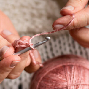 hands-crocheting-with-pink-ball-yarn