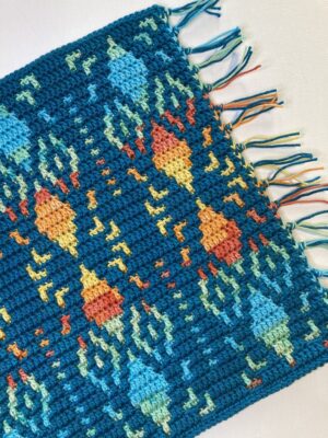 mosaic crochet table runner in shades of yellow orange blue and green on teal
